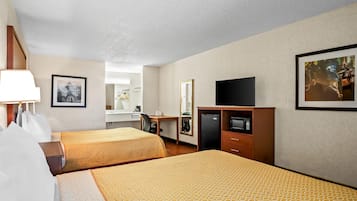 Habitación de hotel con dos camas, un escritorio, un televisor y un espejo.