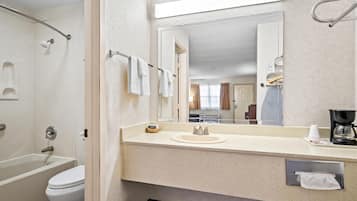 Un baño moderno con bañera, inodoro, lavabo y un espejo grande.