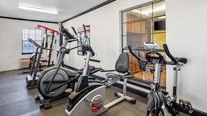 Une salle de sport équipée de vélos d’appartement, d’un tapis de course et d’appareils de musculation.
