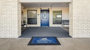 L’entrée de l’hôtel America’s Best Value Inn à Midland, au Texas, se distingue par une porte bleue, une décoration en forme d’étoile et un paillasson portant le nom de l’hôtel.
