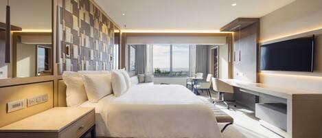 Una habitación de hotel moderna con una cama grande, un escritorio, un televisor y vistas a la ciudad.