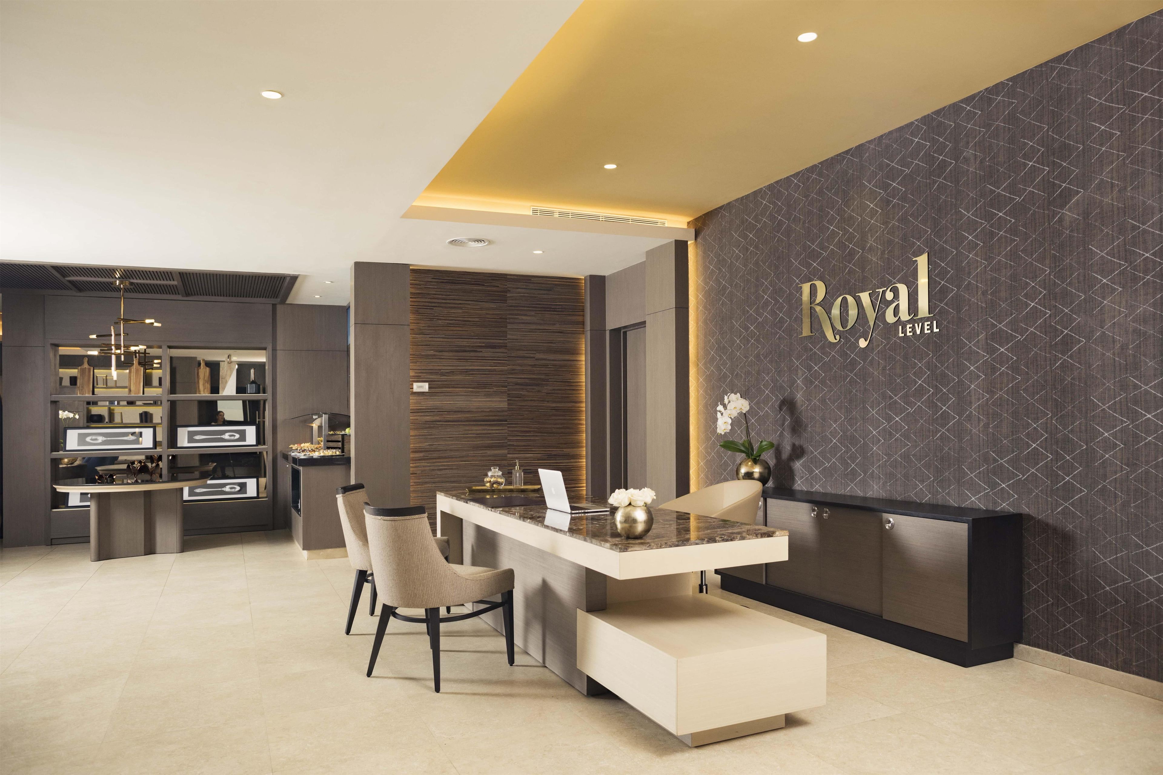 A modern reception area with a marble counter, a seating arrangement, and a wall with the text 'Royal Level'.