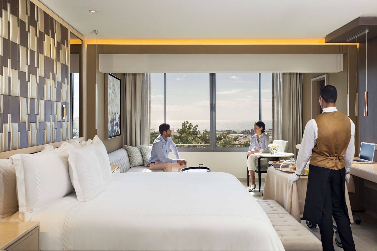 Ein Hotelzimmer mit einem großen Bett, einem Schreibtisch, Blick auf die Stadt und einem modernen Wanddesign.