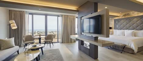 Een moderne hotelkamer met een grote televisie, een bank, een eettafel en een bed.