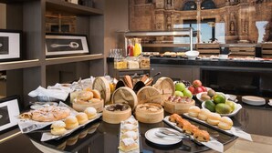 A buffet with various food items, including pastries, fruits, and condiments.