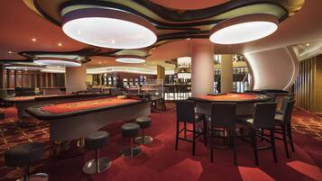 A casino with a roulette table, blackjack tables, and slot machines.