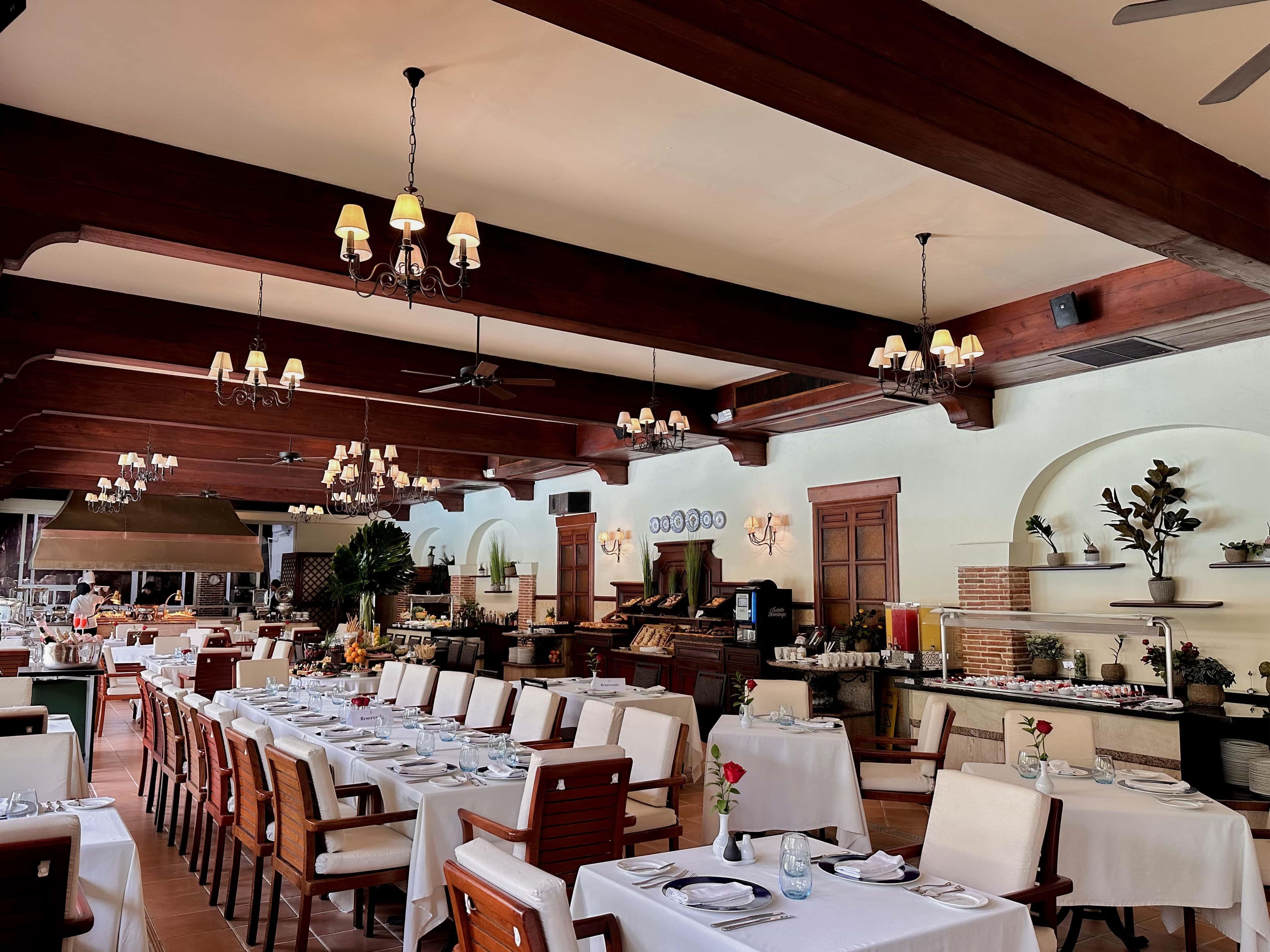 A restaurant with multiple dining tables, chairs, and a variety of lighting fixtures.