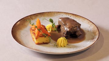 A plate with a piece of meat, potatoes, and a sauce.