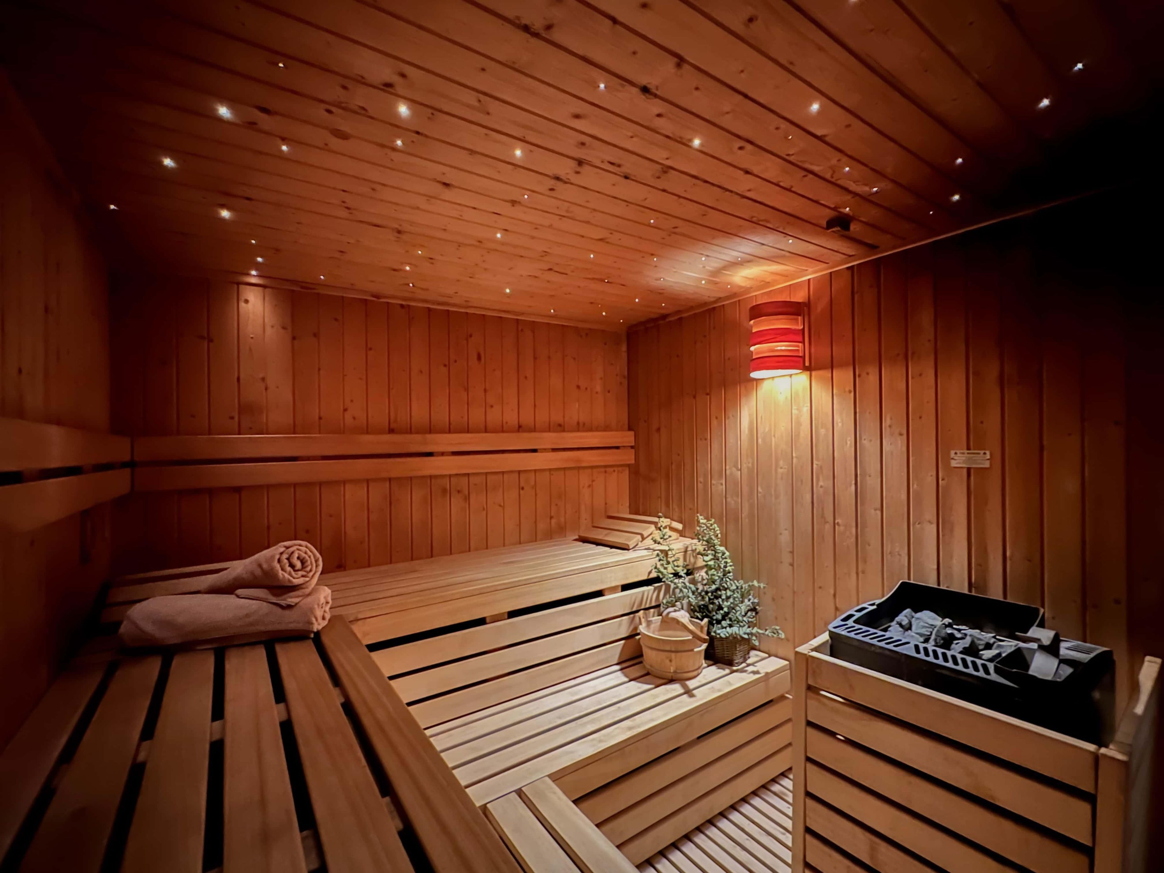 Een sauna met houten banken, een handdoek, een emmer en een verwarming.