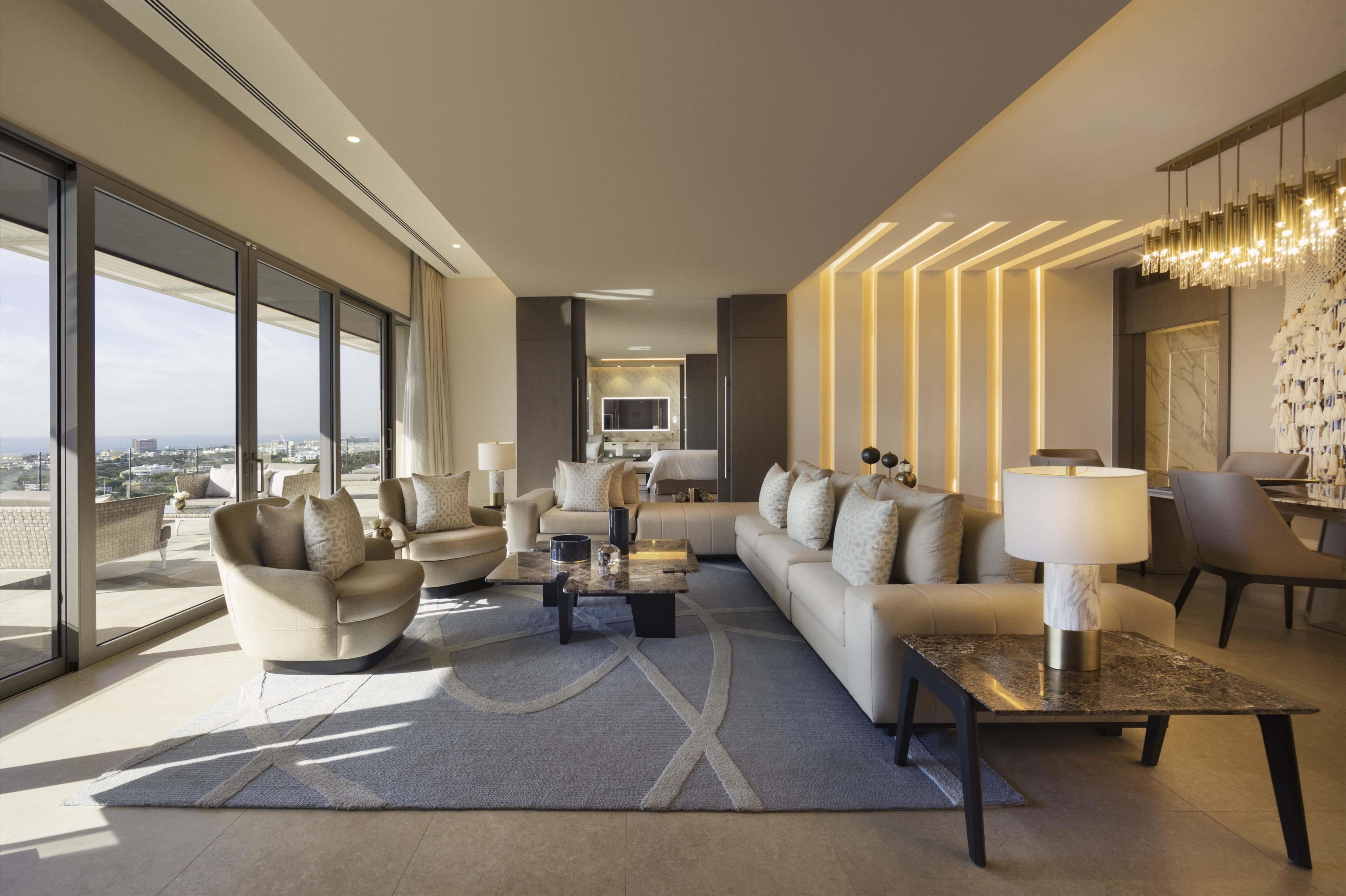 A modern living room with a sofa set, a coffee table, and a dining area with a chandelier.