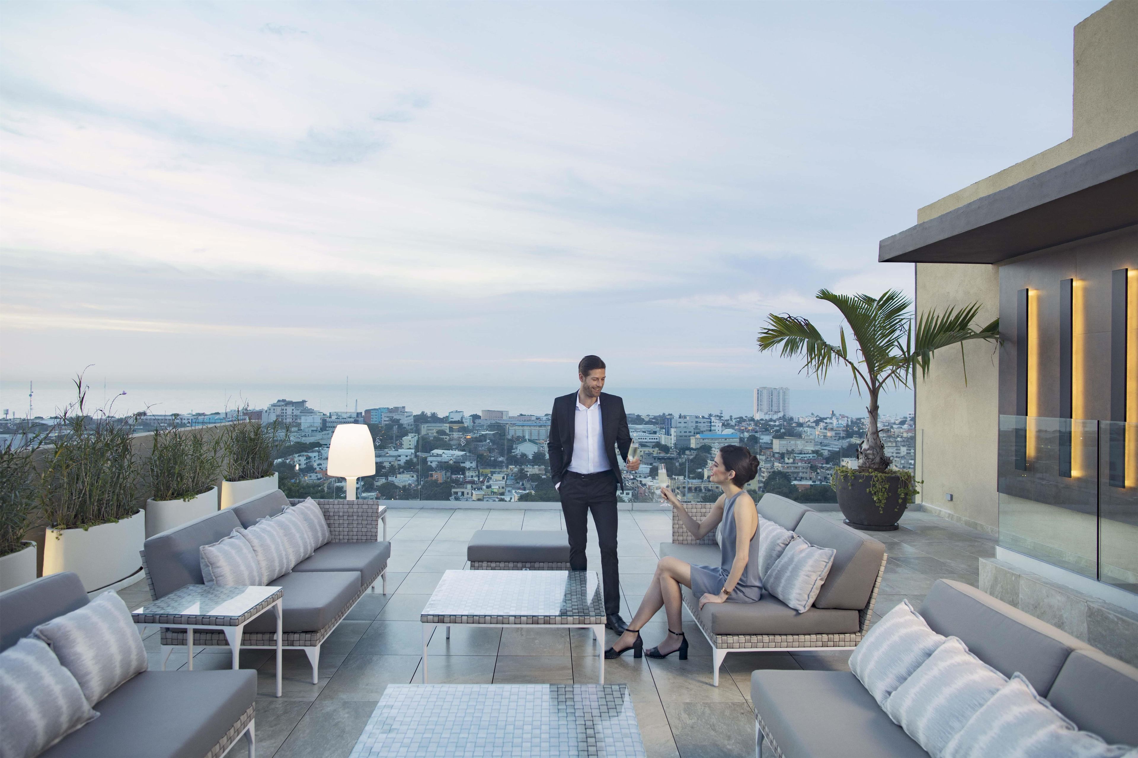 Terraço no telhado com vista para a cidade, área de estar ao ar livre e um vaso com planta.