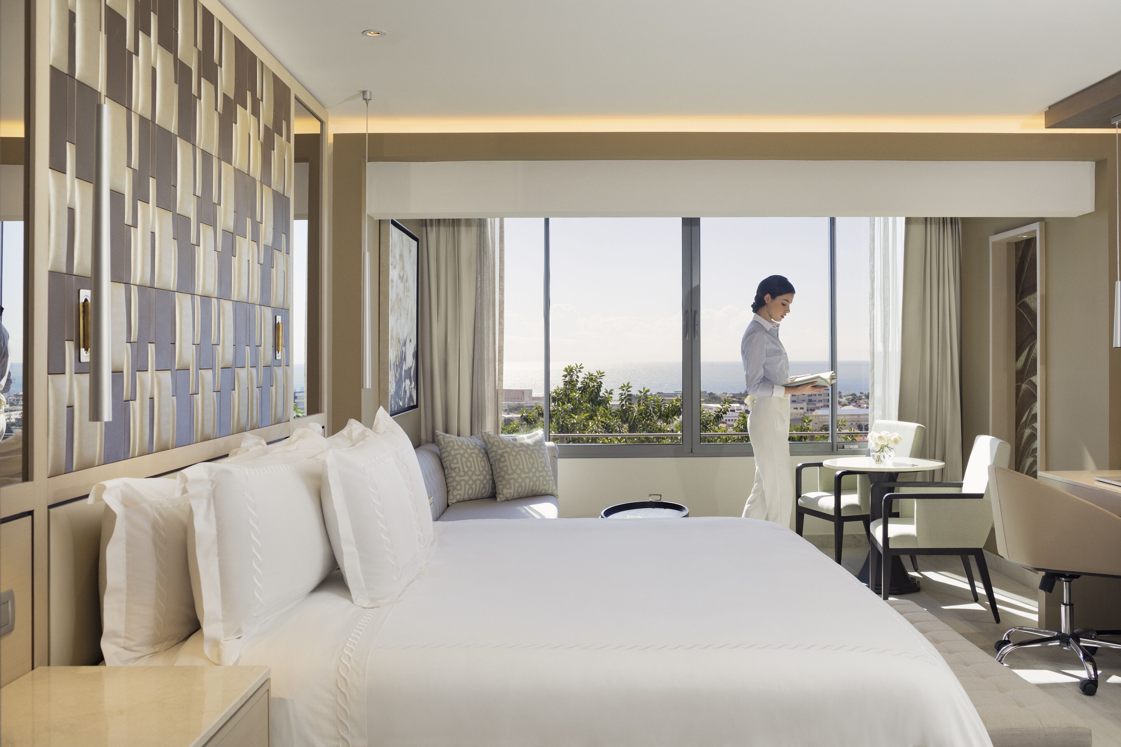A hotel room with a large bed, a desk, and a view of the city.