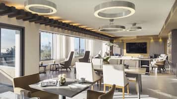 Un comedor moderno con techos altos, lámparas circulares y grandes ventanales que ofrecen vistas al exterior.