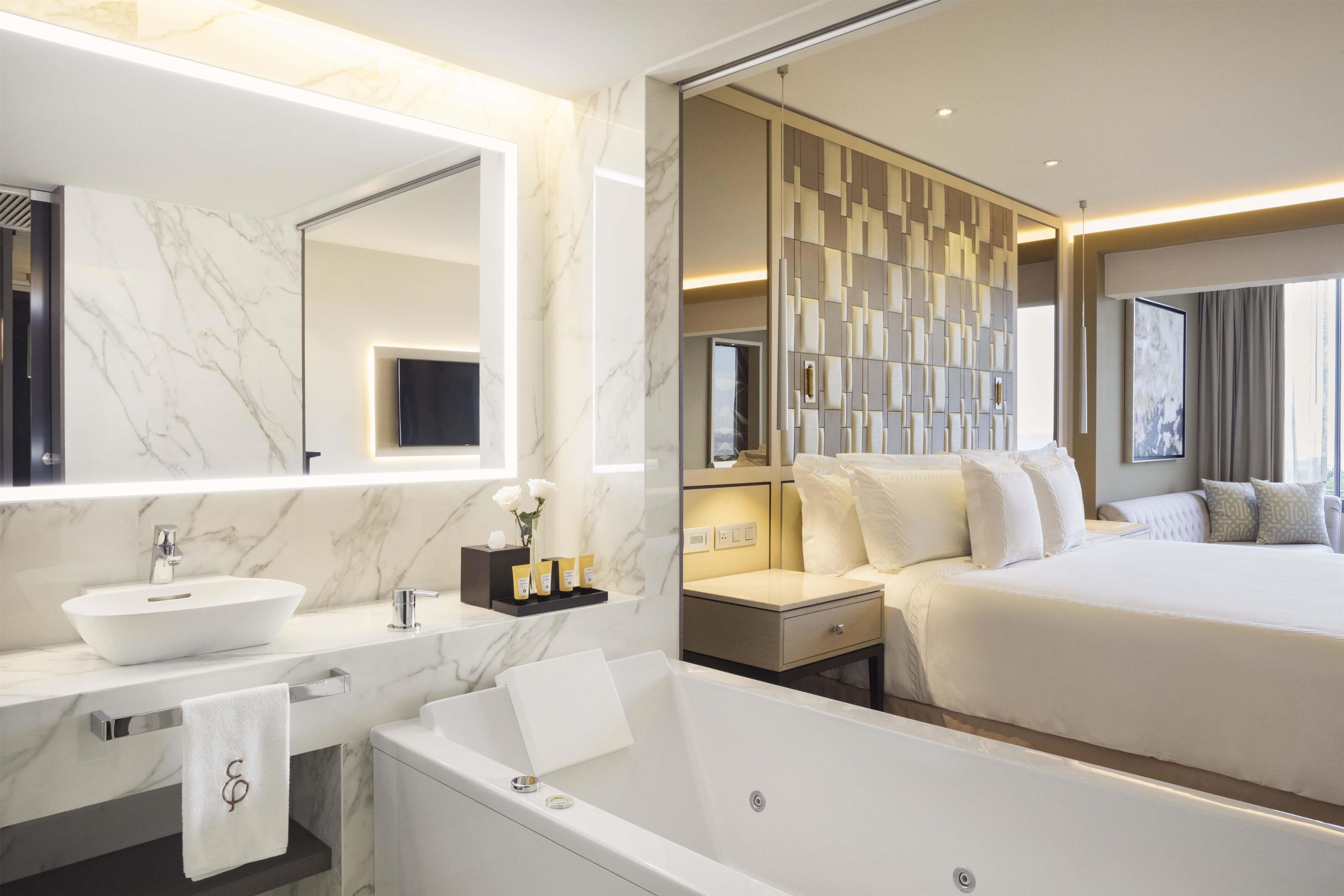 A modern hotel room with a marble bathroom, a large bed, and a wall-mounted TV.