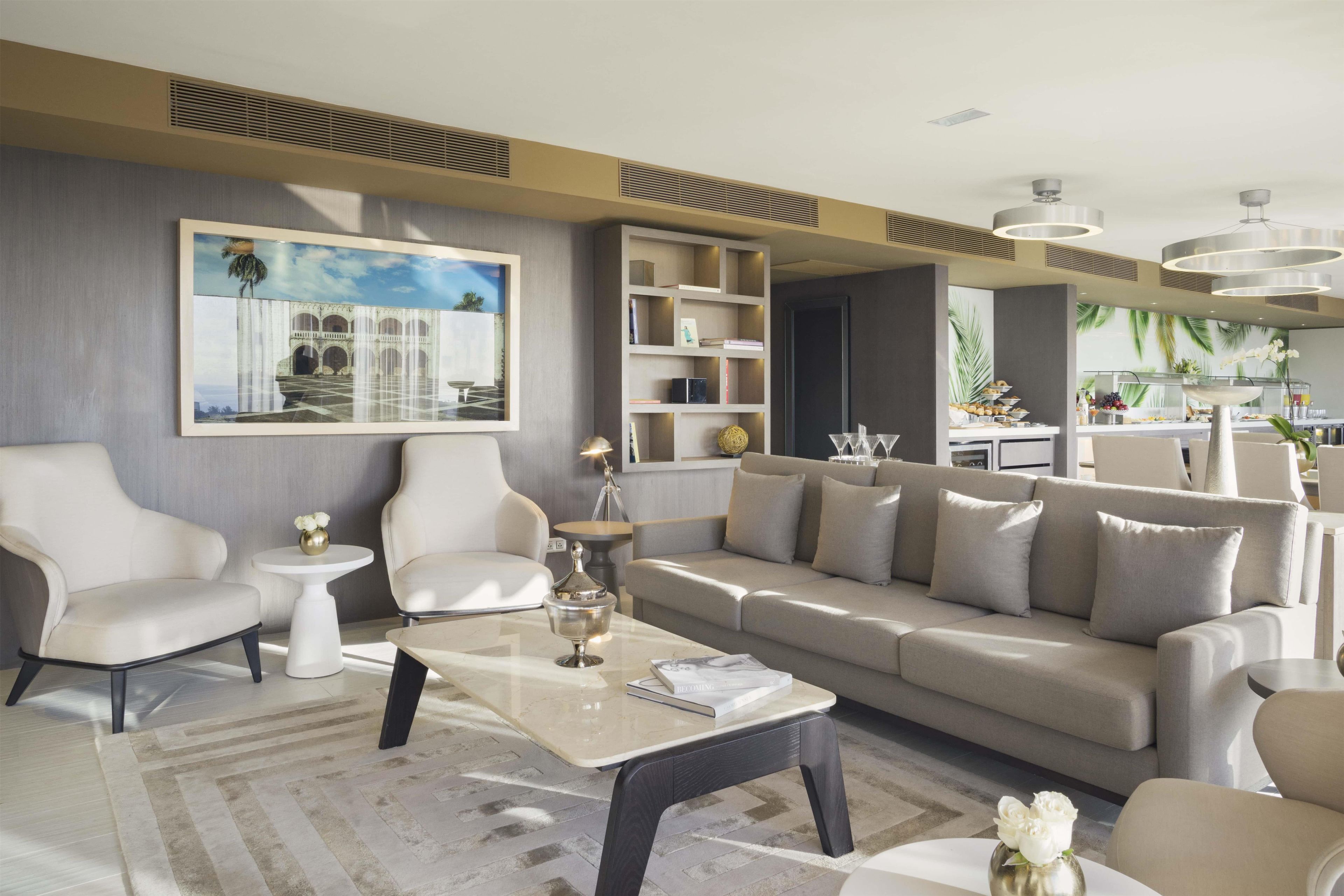 A modern living room with a sofa, armchairs, a coffee table, and a bookshelf.
