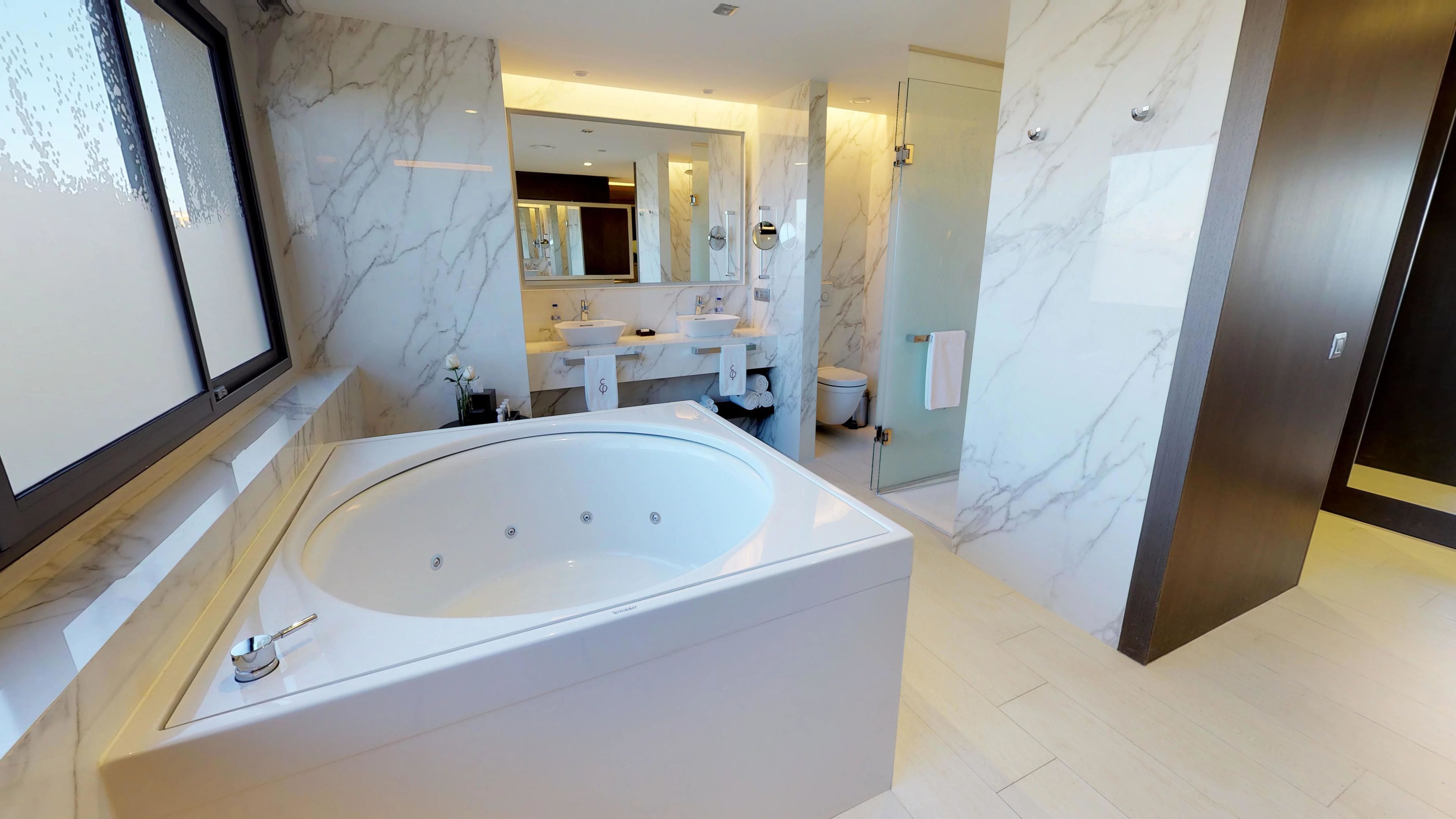 Un baño moderno con una bañera independiente grande, un tocador doble y una zona de ducha con cerramiento de vidrio.