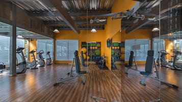 A gym with exercise equipment, wooden flooring, and large windows.
