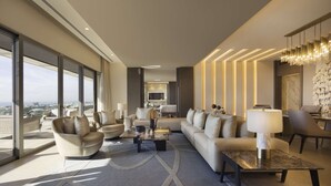 A modern living room with a sofa, armchairs, a coffee table, and a dining area with chairs.