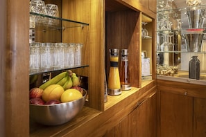 A wooden bar area with a fruit bowl, glassware, and a blender.