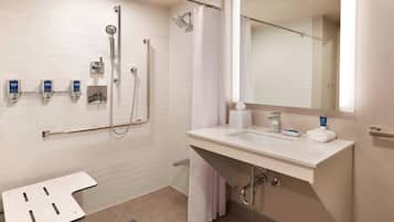 Un baño moderno con ducha, lavamanos y espejo.