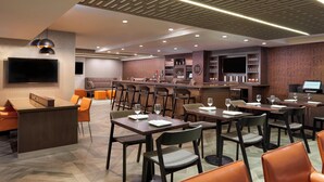 A modern restaurant with a bar area, multiple tables and chairs, and a flat-screen TV mounted on the wall. - Four Points by Sheraton Hamilton - Stoney Creek (Hamilton)