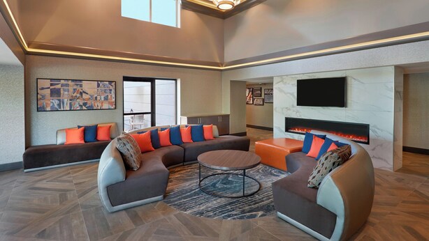 A spacious living area with a sectional sofa, a round coffee table, and a fireplace. - Four Points by Sheraton Hamilton - Stoney Creek (Hamilton)