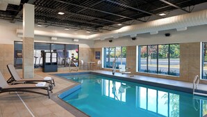 An indoor swimming pool with lounge chairs, exercise equipment, and large windows offering views of the outside. - Four Points by Sheraton Hamilton - Stoney Creek (Hamilton)