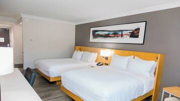 A hotel room with two single beds, a desk, and a chair.