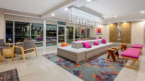 A modern living room with a grey sectional sofa, wooden chairs, and a colorful rug. - La Quinta Inn & Suites by Wyndham Seattle Federal Way (Federal Way)
