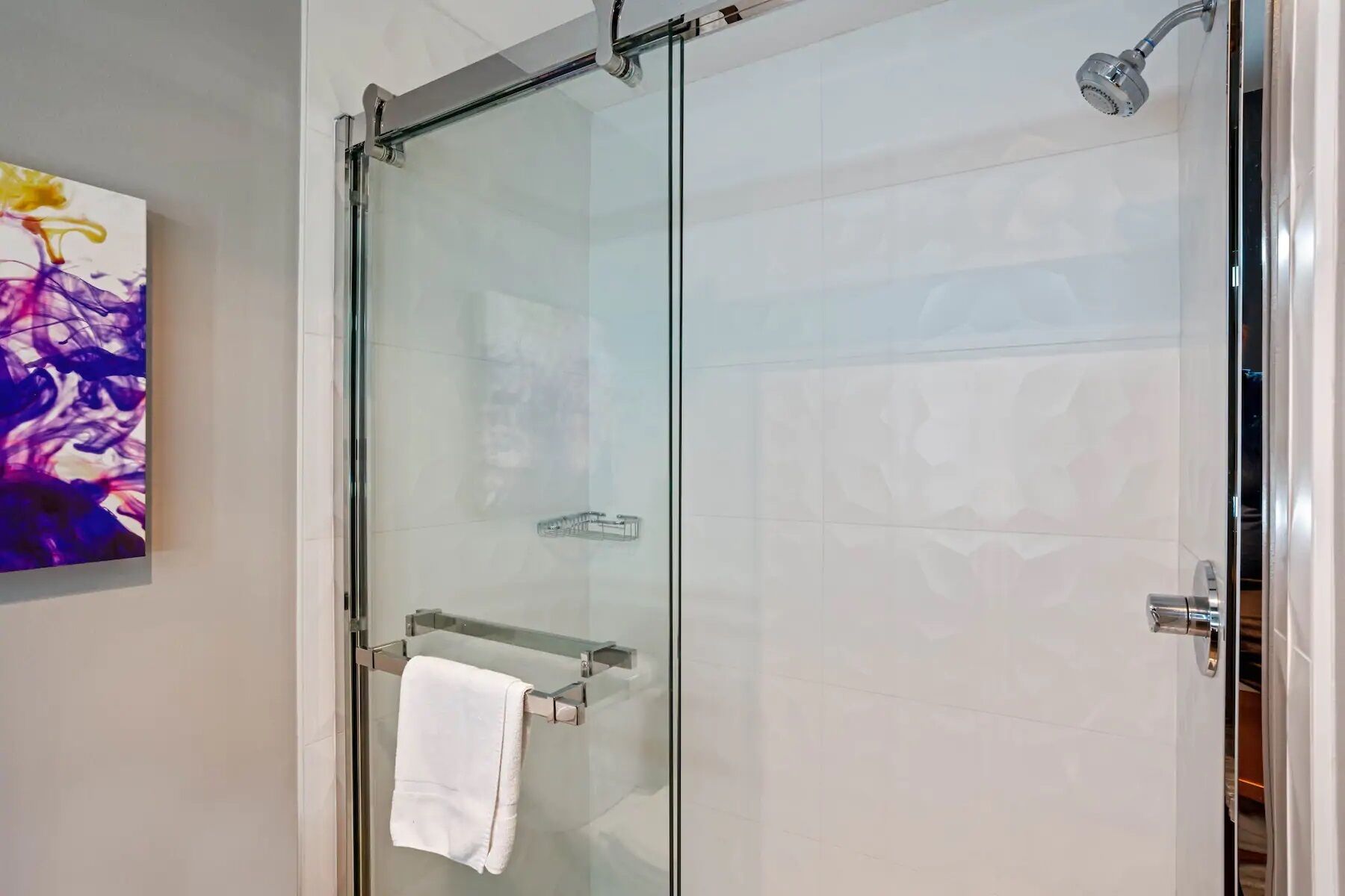 A glass-enclosed shower with a towel rack and a glass door.