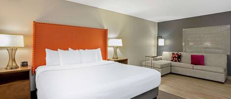 A hotel room with a large bed, a sofa, and a wall-mounted TV.