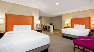 A hotel room with two beds, a desk, and a chair.