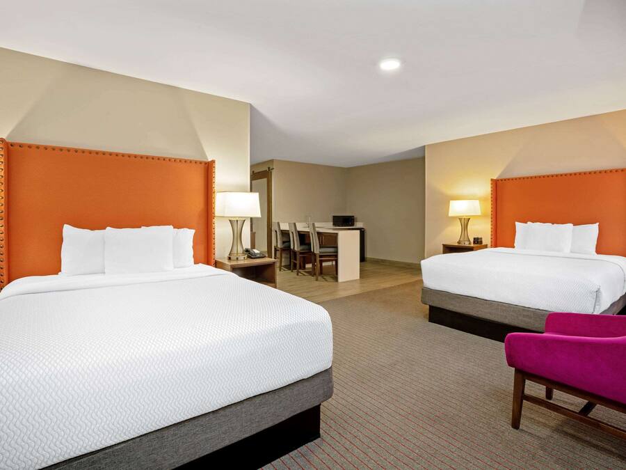 A hotel room with two beds, a desk, and a chair.