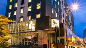 Un hôtel moderne avec une façade en verre, de nombreux étages et un hall d’entrée imposant.