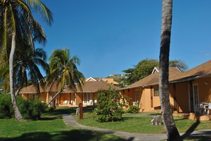 Un resort con varias construcciones tipo bungaló, cada una con un porche y mobiliario exterior.