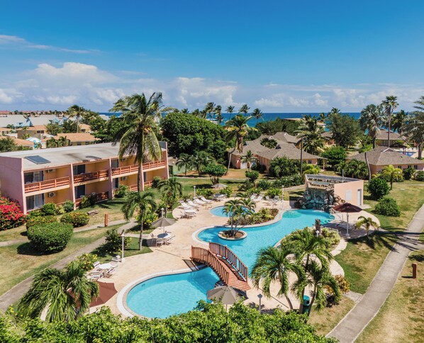 Ein Resort mit großem Schwimmbad, mehreren Gebäuden und Palmen.