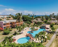 Un resort con una amplia piscina, varias edificaciones y palmeras.