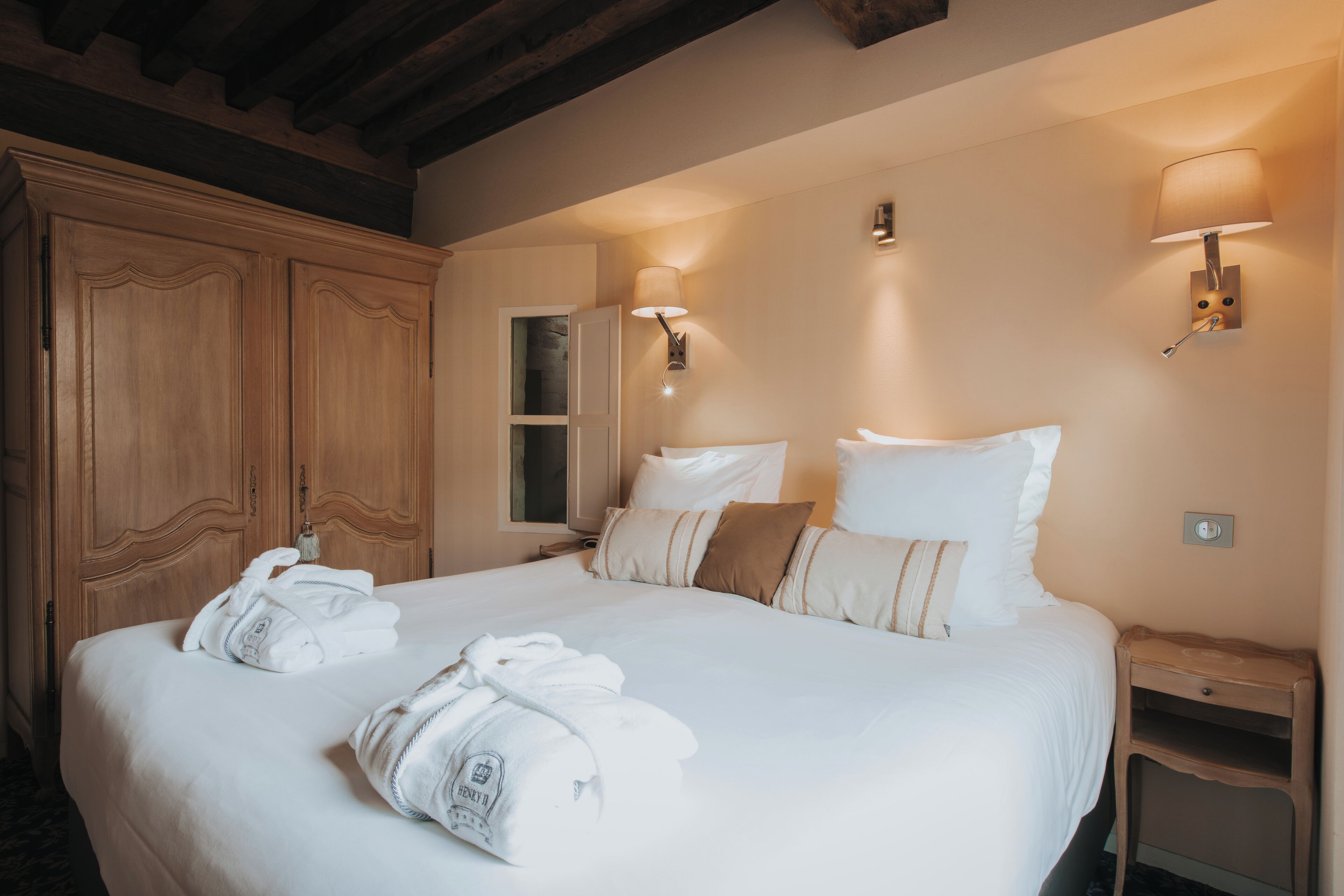 A hotel room with a large bed, two bedside lamps, a wooden wardrobe, and a mirror.