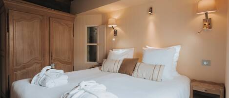 A hotel room with a large bed, two bedside lamps, a wooden wardrobe, and a mirror.