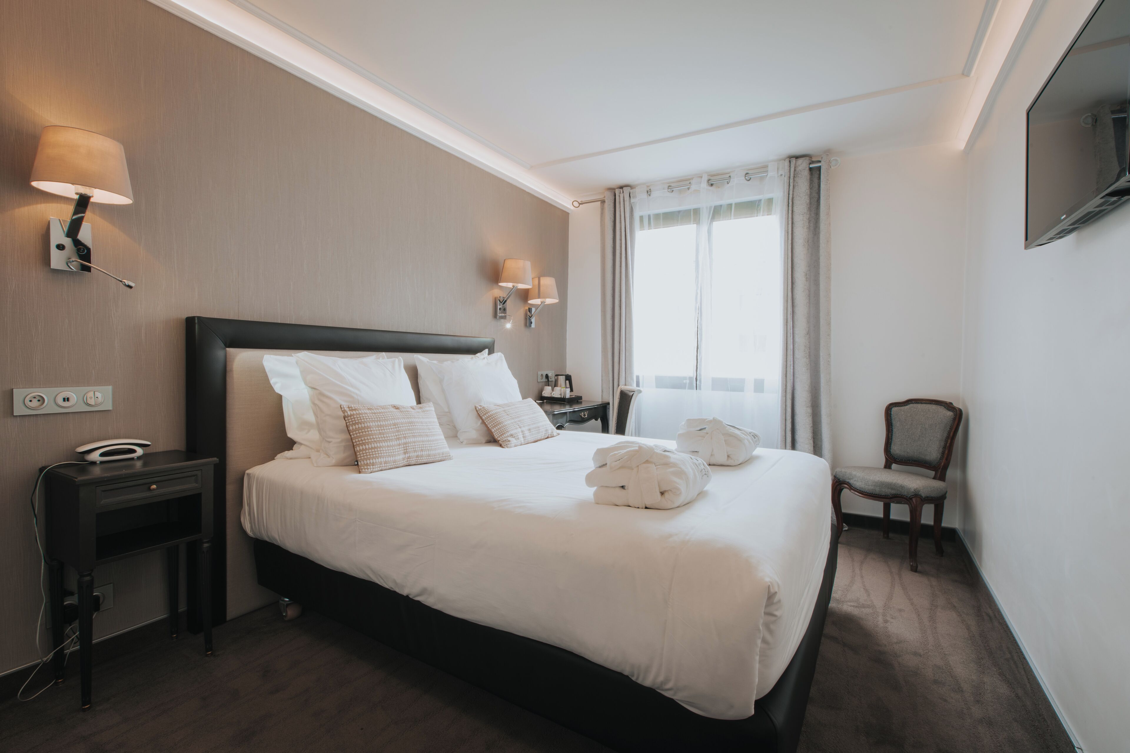 Une chambre d’hôtel avec un grand lit, des tables de chevet, un bureau et une chaise.