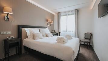 Une chambre d’hôtel avec un grand lit, des tables de chevet, un bureau et une chaise.