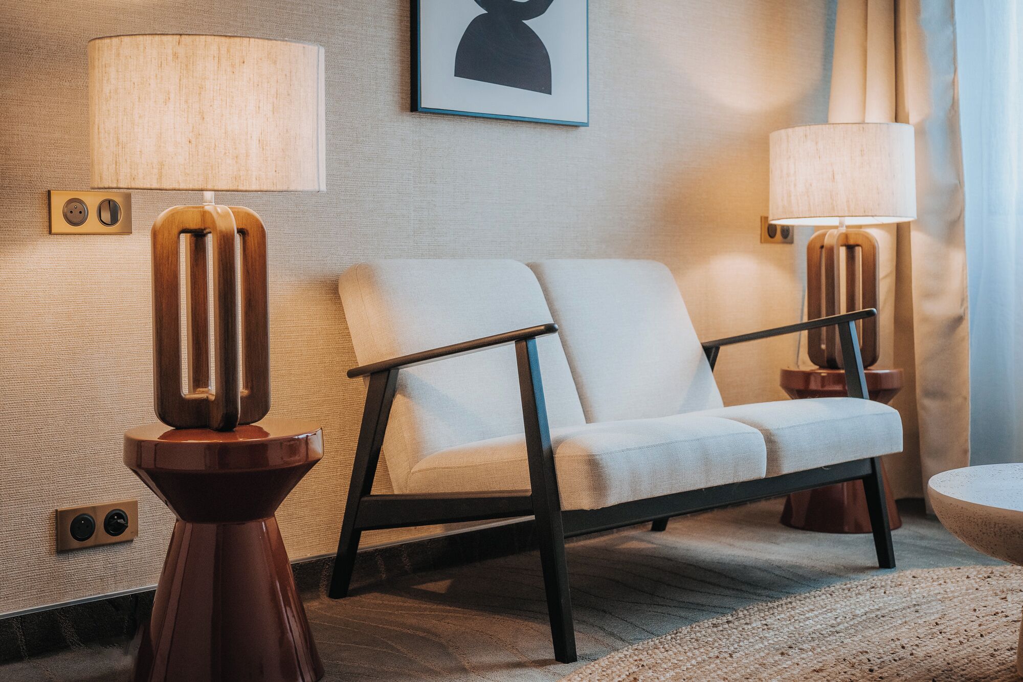 A modern living room with a sofa, two floor lamps, and a framed picture on the wall.
