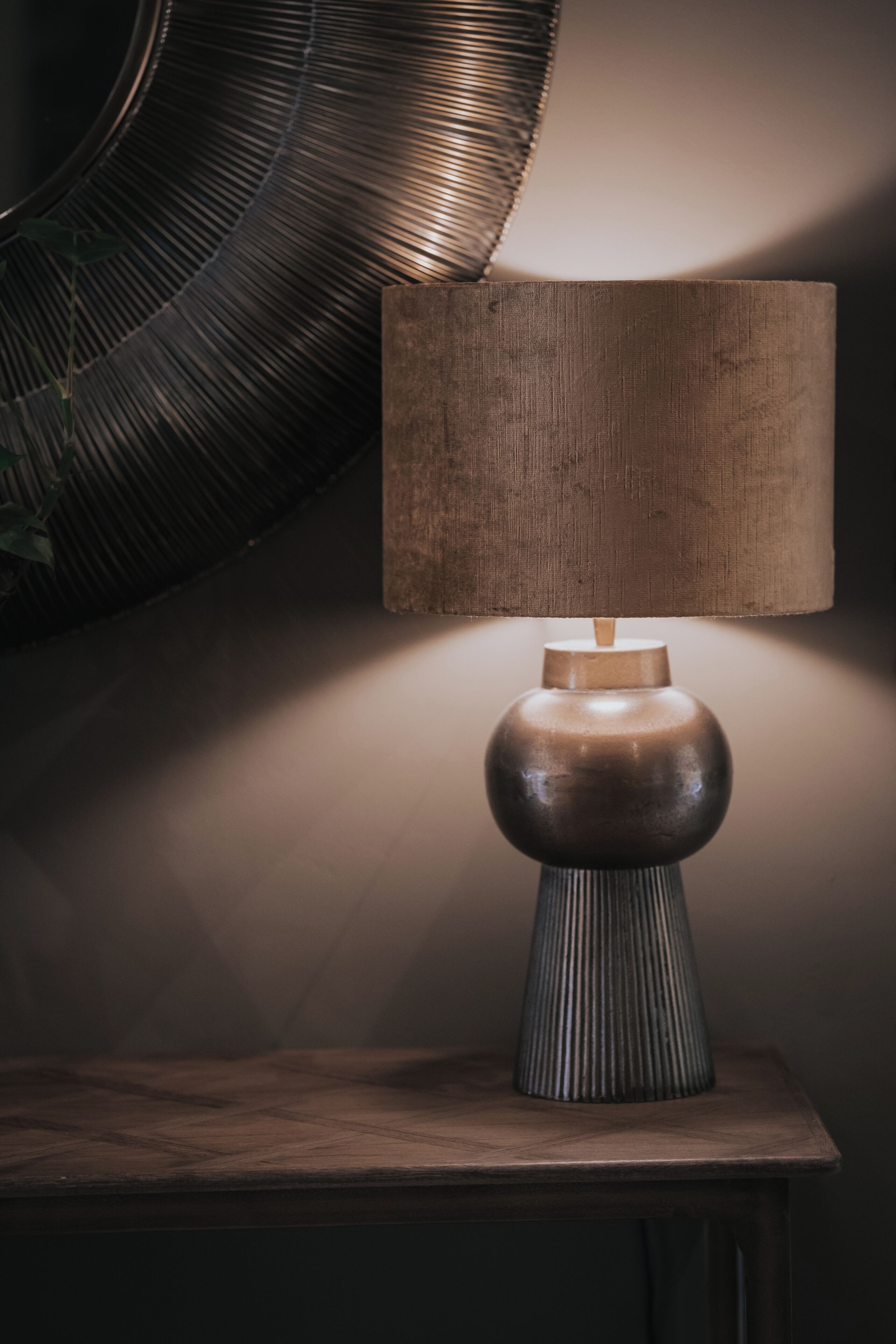 A modern table lamp with a wooden base and a textured lampshade on a wooden table.