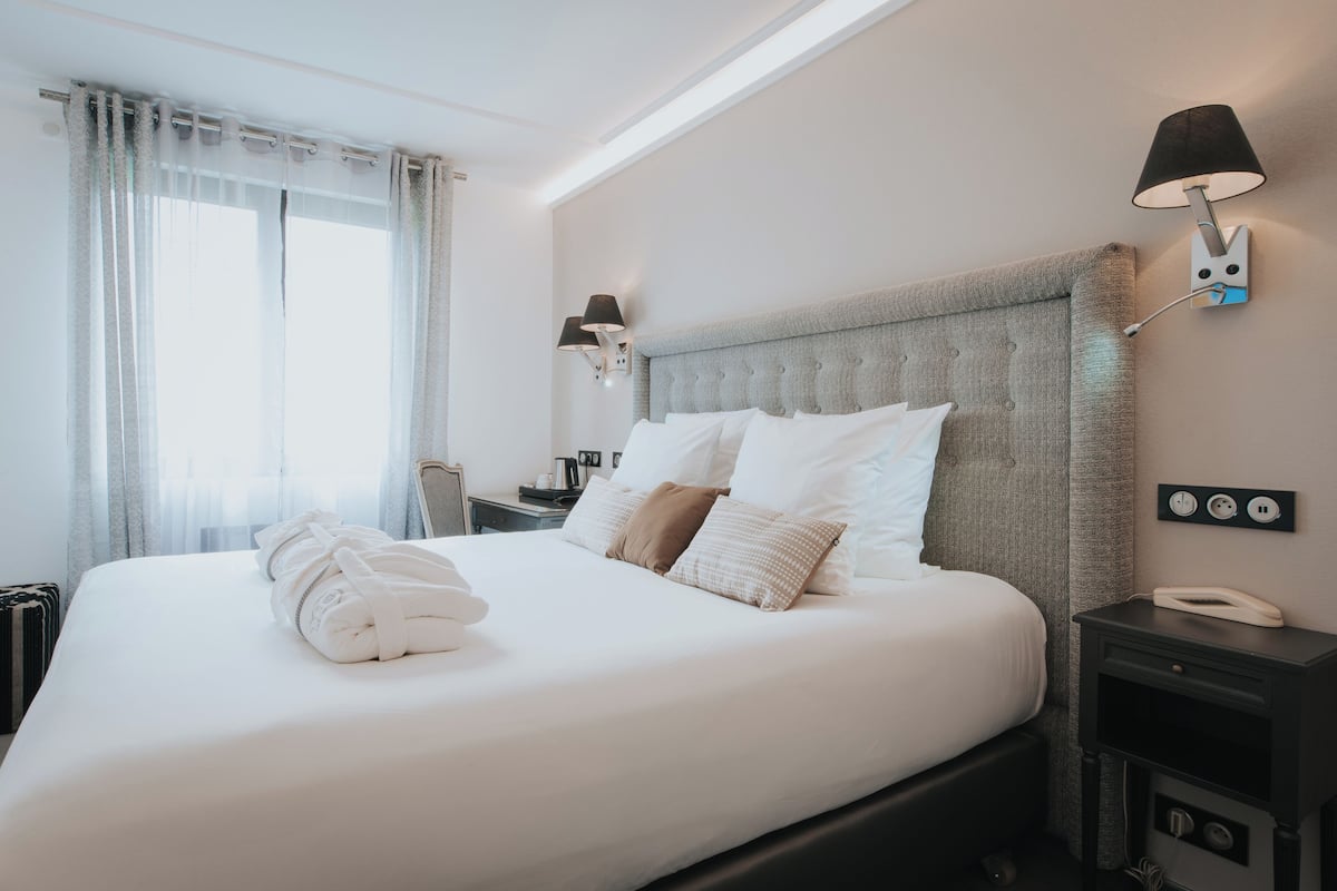 A hotel room with a large bed, a bedside table with a lamp, and a telephone.