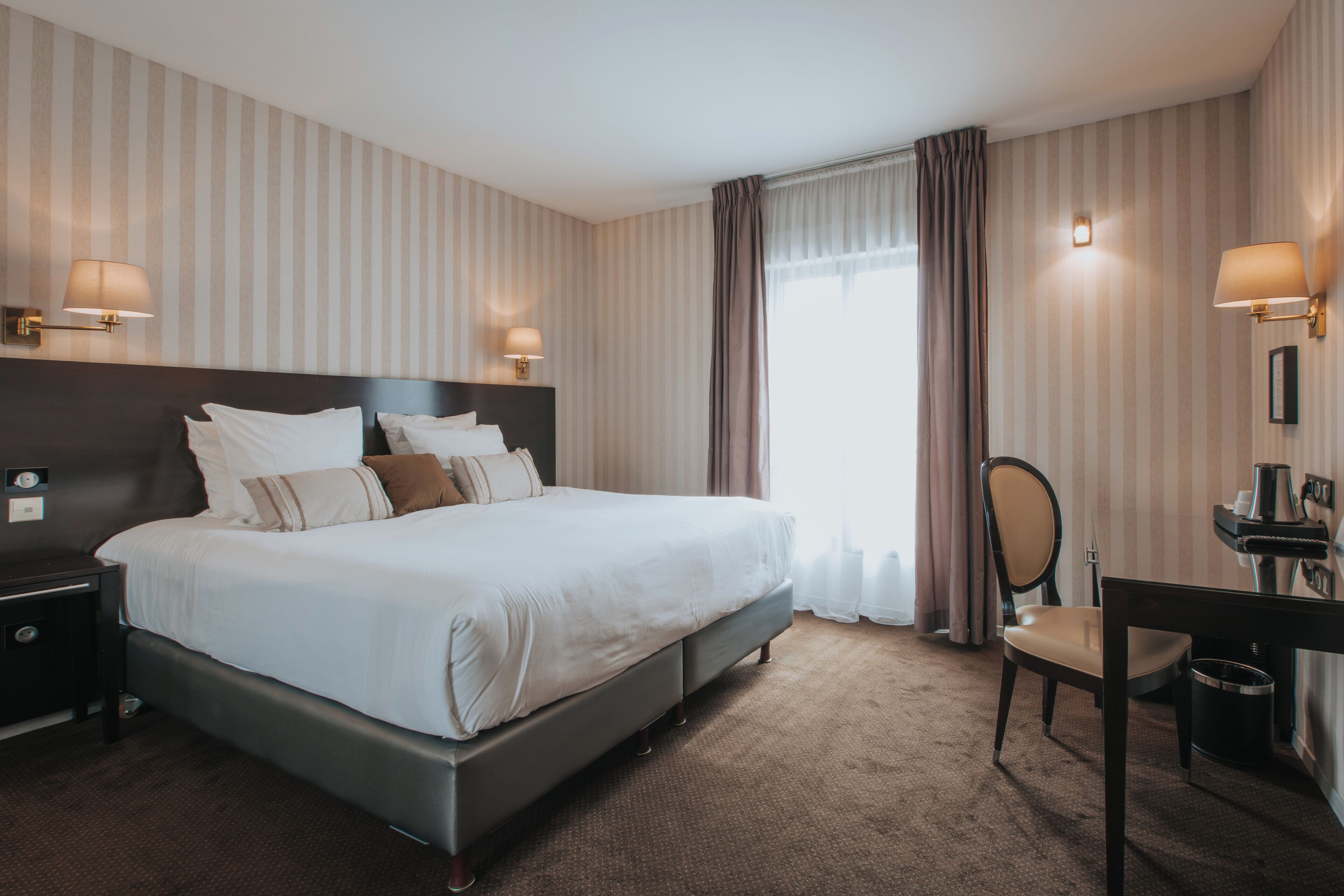 Une chambre d’hôtel avec un grand lit, des lampes de chevet, un bureau et une chaise.