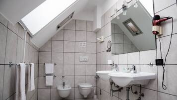 Een moderne badkamer met twee wasbakken, een toiletbril en een dakraam.