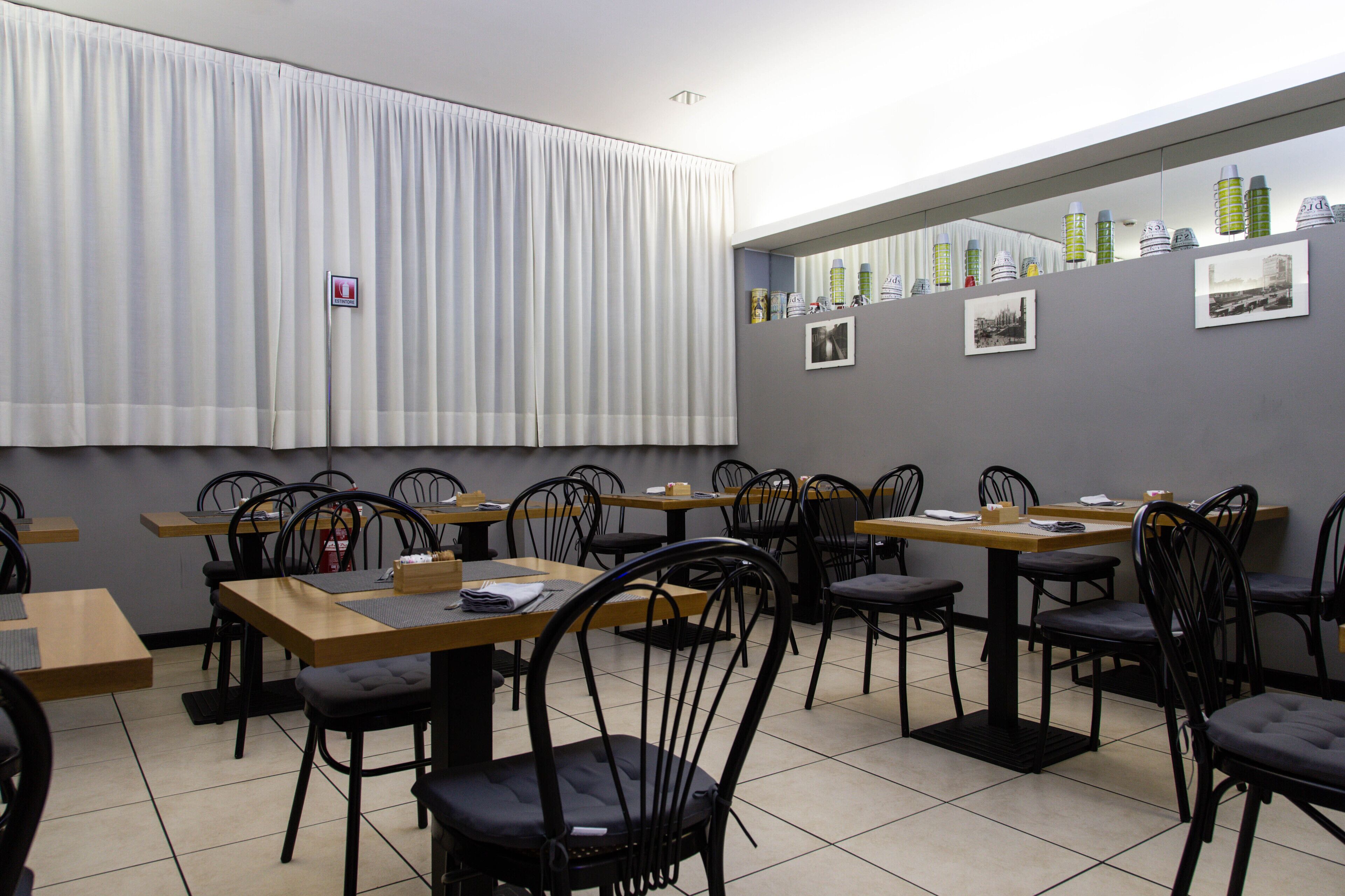 A restaurant with multiple tables and chairs, a fire extinguisher, and a mirror on the wall.