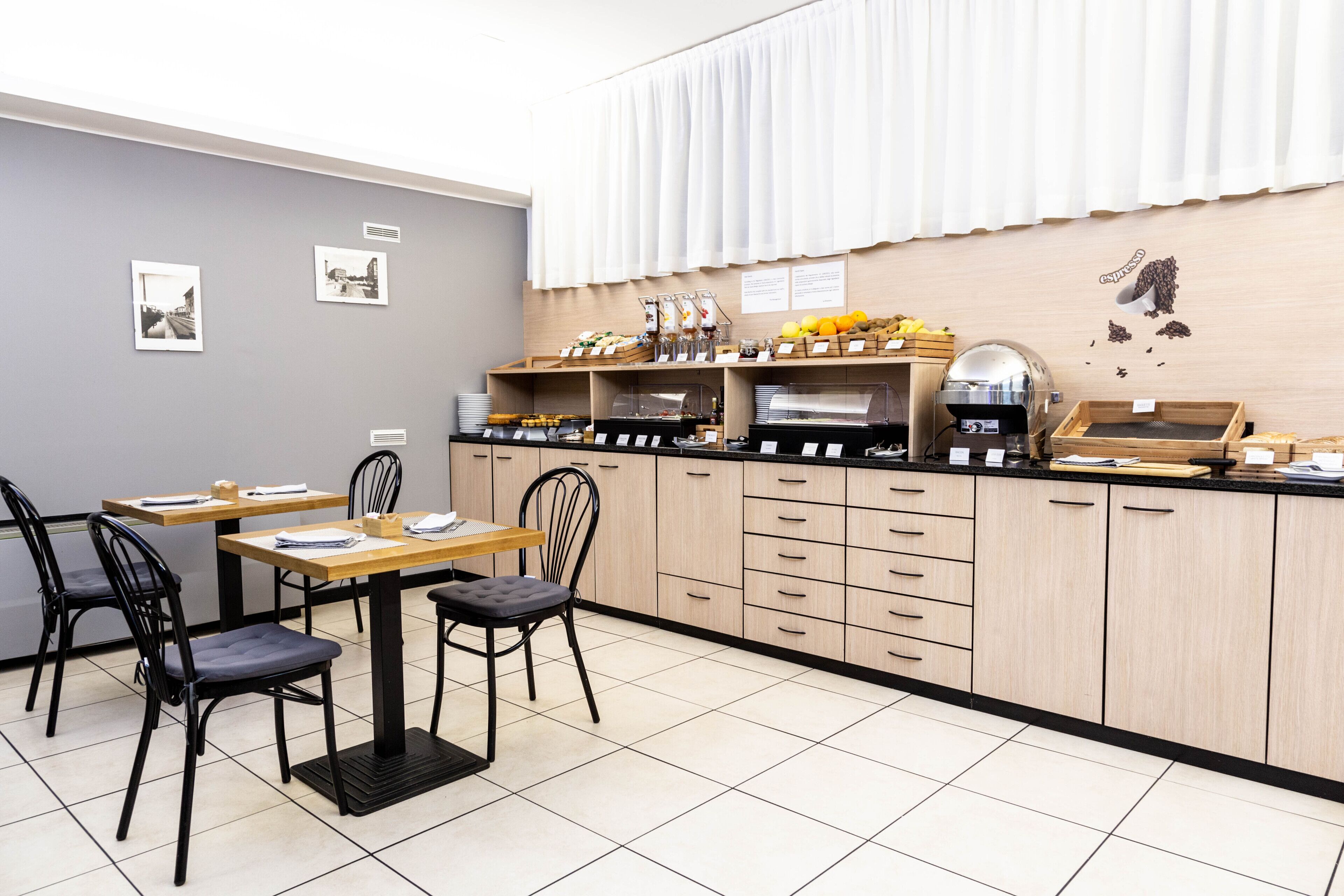 A modern cafe with a wooden counter, black chairs, and a tiled floor.