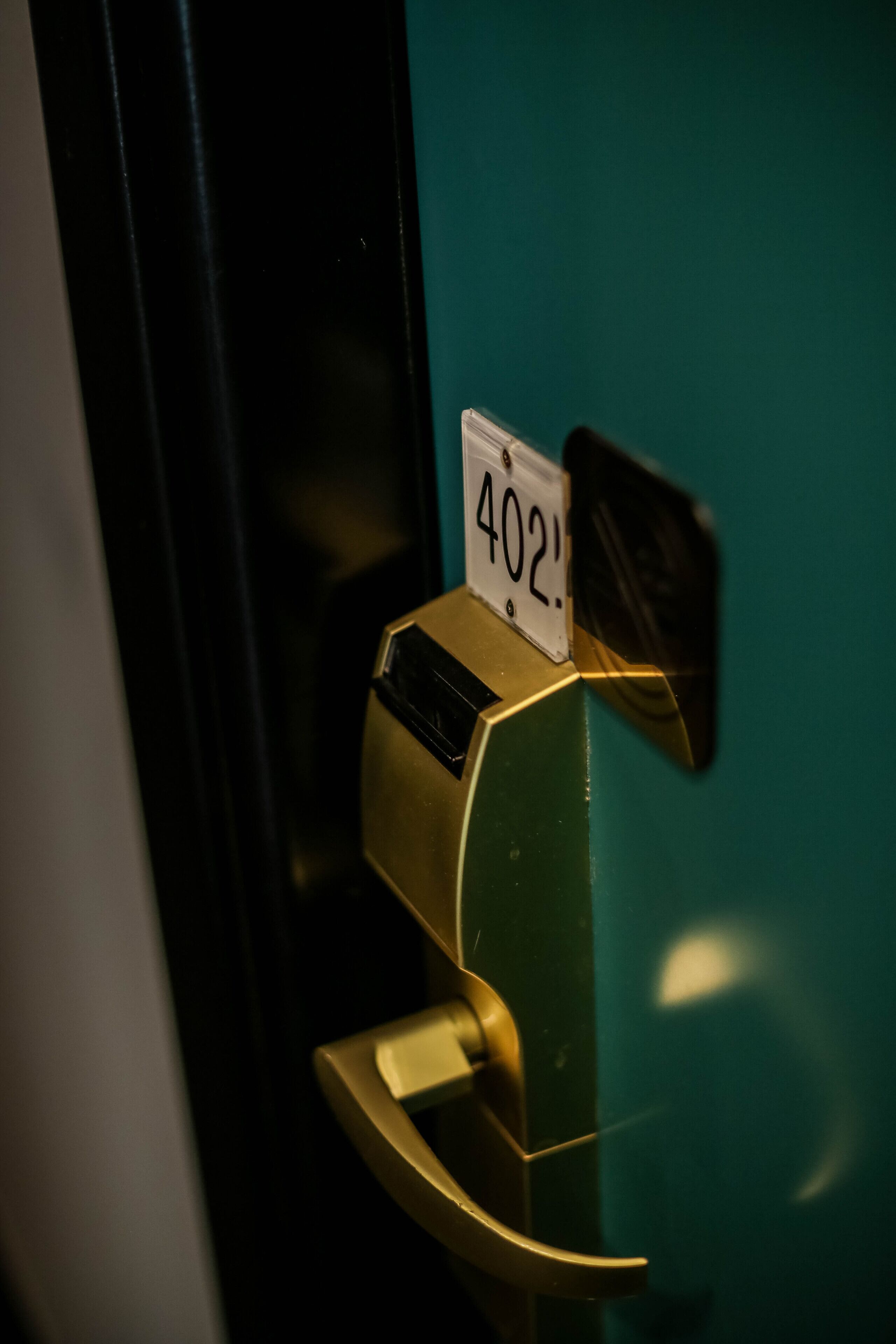 A door with a brass handle and a white sign displaying the number 402.