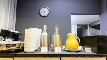 Ein Frühstücksbuffet mit Kaffeeautomaten, Milchspendern und einem Saftkrug.